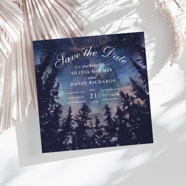 Spara datumkortet i Starry Nght Forest Spara Datumet (Starry Night Forest Save The Date Card on a white boho table with dry palm leaf.)