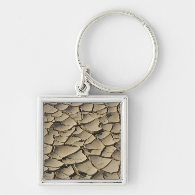 Sprickig lera formation i dalbotten av fyrkantig silverfärgad nyckelring (Framsidan)
