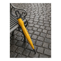 Stängd gul paraply bredvid parkbänk