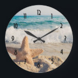 Starfish on a Sandy Beach Photographic Stor Klocka<br><div class="desc">En klocka med ett scenfoto. En stor stjärnfisk satte sig upprätt på en sandstrand. Ett vackert blåhav med vågar av vit surfa i bakgrunden.</div>