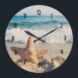 Starfish on a Sandy Beach Photographic Stor Klocka<br><div class="desc">En klocka med ett scenfoto. En stor stjärnfisk satte sig upprätt på en sandstrand. Ett vackert blåhav med vågar av vit surfa i bakgrunden.</div>