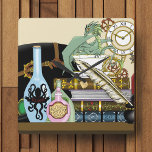 Steampunk Dragon Fyrkantig Klocka<br><div class="desc">Grönt drakar i ett kopp i te som ligger på en hög av bokar. Top hat,  elixirer,  en luddpenna med bläckbrunn och en klocka med växlar som visar sig är alla runt draken.</div>