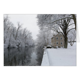 Stilla hus längs lugnt vatten i snö hälsningskort