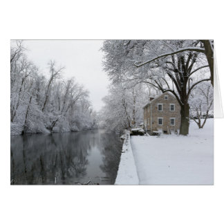 Stilla hus längs lugnt vatten i snö hälsningskort