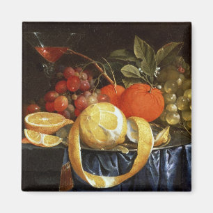Stilleben av druvor, orangar och en skalad citron magnet