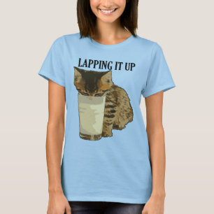 Sugande det sött randig katt som dricker mjölk frå t shirt