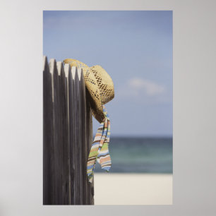 Sugrörhatt som hänger på staket på stranden poster