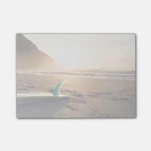Surfingbrädan lägger på stranden, som solen vis post-it block