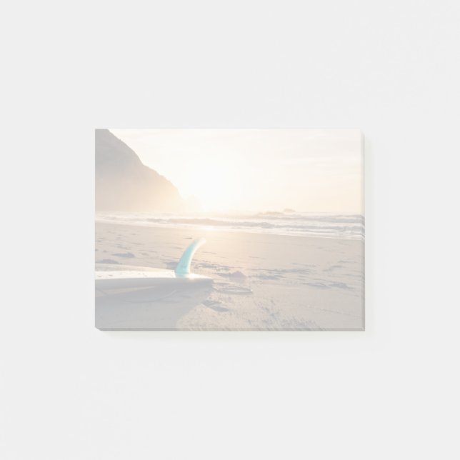 Surfingbrädan lägger på stranden, som solen visas post-it block (Framsida)