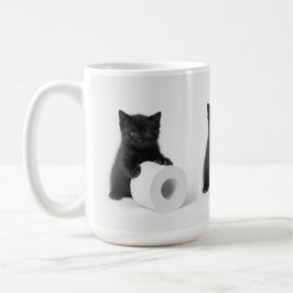 Svart kattunge vaktar toarulle på kaffemugg