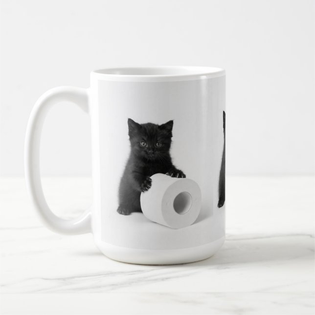Svart kattunge vaktar toarulle på kaffemugg (Vänster)