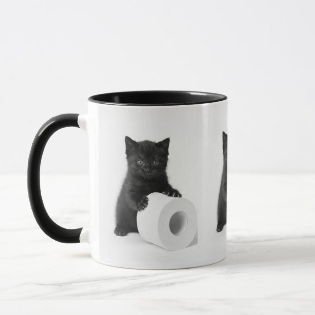 Svart kattunge vaktar toarulle på mugg (Vänster)