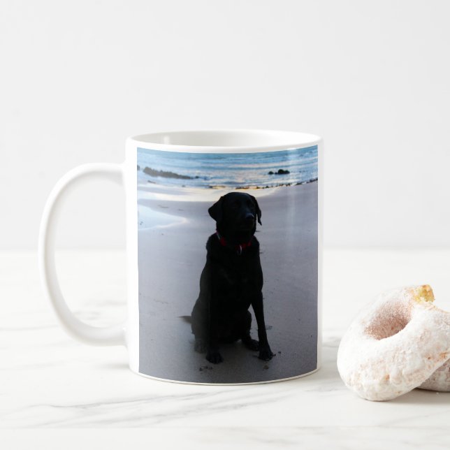 Svart Labrador på en strand Kaffemugg (Med munk)
