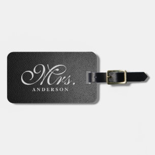 Svart läderbakgrund med monogrammat bagagemärke bagagebricka