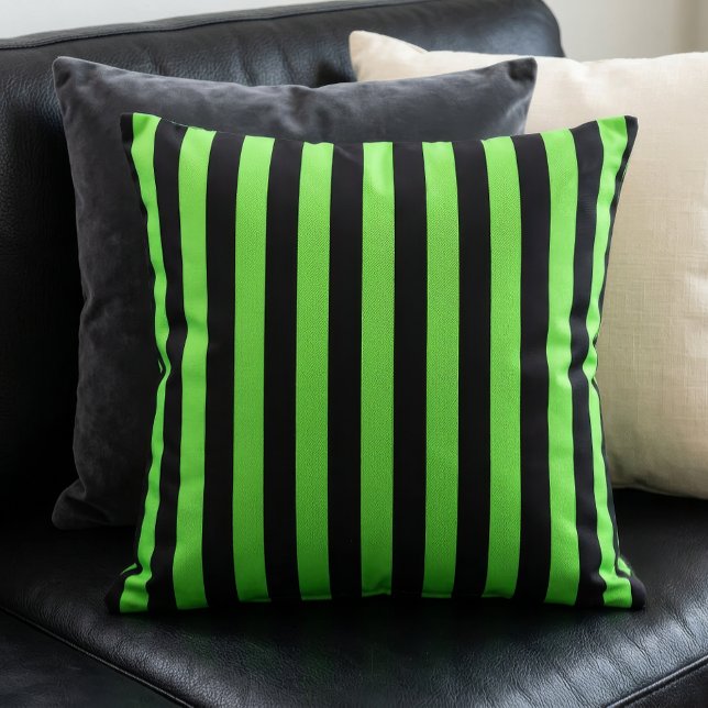 Svarta och limegröna randiga mönster kudde (A lime green and black stripes pillow sits on a black couch in front of other pillows.)