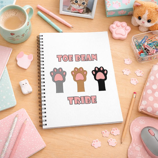 Tåbönsstammen Roliga Kattfötter Rosa Anteckningsbok (A notebook with cat paws and the words toe bean tribe in pink letters with gray outlines.)