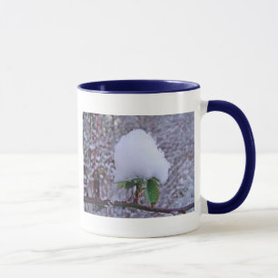 Tasse Schnehäufchen auf hübscher Pflanze Mugg