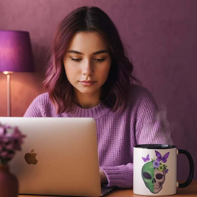 Taza blanca con diseño calavera alien y mariposa – mugg (Una joven mirando sus cosas en el ordenador mientras se toma una bebida caliente en su taza favorita)