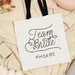 Team Bride Modern Script Guld Bröllop Namn Tygkasse<br><div class="desc">Den här moderna toteväskan med ett skript med minimal avslappnad och kalligrafi av chicen som läser TEAM BRIDE, liksom det anpassade namnet på maid of honor eller briderna, gör att linjer blir rent för att skapa ett slimmat och sofistikerat utseende. Den underskattade stil med den lilla tryckta guld-hjärtdetaljen gör hennes...</div>