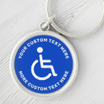 Text för handikappade handikappade symboler blå, v rund silverfärgad nyckelring<br><div class="desc">Rund,  handikappad nyckelkedja med vit inaktiverad symbol på blå bakgrund och vit,  cirkelformad text.</div>