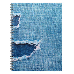 Texturerad denim-bakgrund. Torn hål i tyget Anteckningsbok