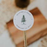 Timber Grove | Winter Pine Tree Wedding Runt Klistermärke<br><div class="desc">Add a rustic winter touch to your event favors with this round sticker from the Timber Grove collection by Redwood & Vine Design Co. Featuring a watercolor evergreen tree and customizable text, this design is perfect for sealing candle tins, favor bags, or gift boxes. Ideal for cozy winter weddings, forest-inspired...</div>