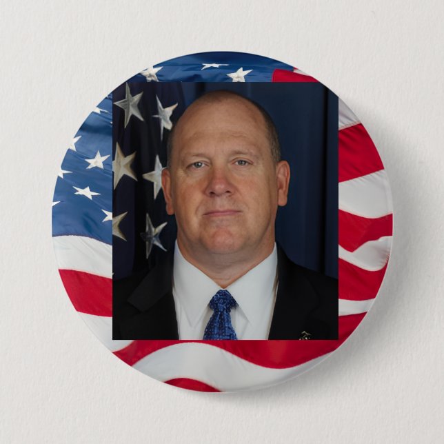 Tom Homan Button with flag waving behind Knapp (Framsida)