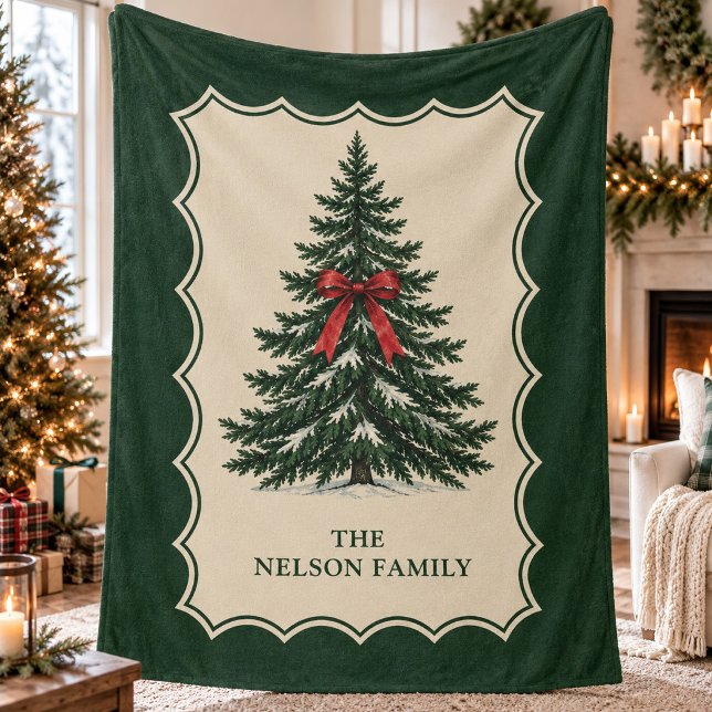 Traditionell Tall Alpin Vinterarv Fleecefilt (Traditional snow-dusted pine tree with a red bow in a cream scalloped border with family name.)