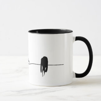 Tre lite fåglar som sitter på en binda mugg