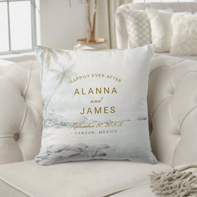 Tropisk akvarell strandbröllopsfoto kudde (Beach-themed wedding pillow with “Alanna and James” and date text on a cream tufted sofa.)
