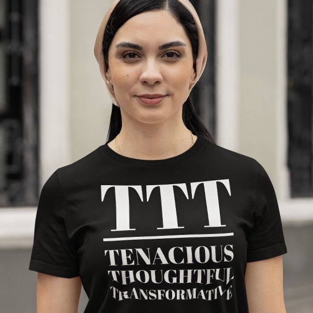 TTT- Tenaciär, tankfull, omvandlande T Shirt (Young woman wears a "TTT: Tenacious, Thoughtful, Transformative" black t-shirt.)