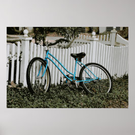 Turkos cykel lutar mot ett vitt staket poster