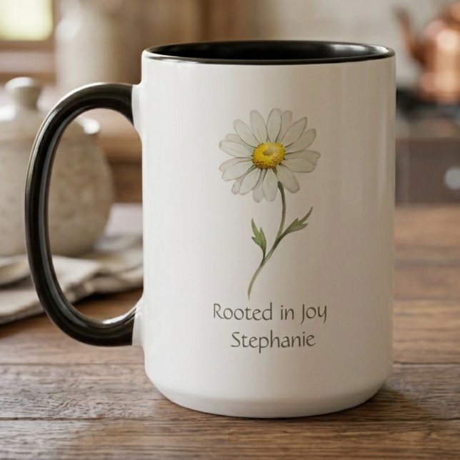 Tusenskönor Botanisk Akvarell Mugg (A "Rooted in Joy" daisy mug sits on a wooden table, a perfect thoughtful gift for her birthday.)
