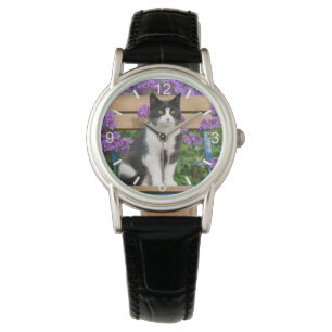 Tuxedo cat sitta på en trädgårdsstol med blommor armbandsur