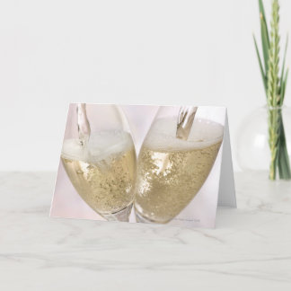 Två champagneflöjter som fylls med sparkling kort