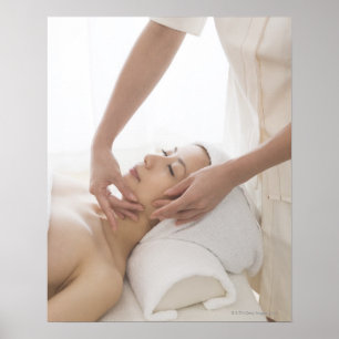 Ung kvinna som har ansikts- massage poster