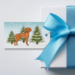 Ungersk Vizsla Hund Snowy Winter Forest Festive Presentetikett<br><div class="desc">Desteis ursprungliga tecknad illustrerar en söt ungersk Vizsla-hund. Hund placeras på en vinterscen med tre gröntar nära träd och fallande snö. Bakgrunden är en blå till vit övertoning som ge kallets vintag. Det finns också ett textområde på andra sidan som nu lyder: "God jul!". En annan textmall har ord: "TO:"...</div>
