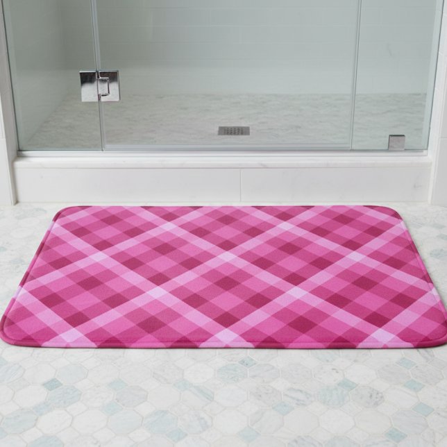 Vacker rosa magenta rutig badrumsmatt medeltand badrumsmatta (Beautiful Pink Magenta Plaid Medium Bath Mat laying on floor in front of a shower in a bathroom.)