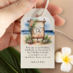 Välkomstpåse för Rustic Beach Destination Wedding Presentetikett<br><div class="desc">Välkomna märkre för att du ska kunna anpassa dina välkomstpåsar. Den här charmerande designen har en vattenfärgsscen med ett romantiskt, rustiskt välkomstbord, på en oceanfront-strand, dekorerad med tropiska blommor. Perfekt för en avslappnad eller ett badbröllop på stranden, chic eller klassens semesterdestination bröllop på stranden. Bakgrund och text har en naturlig...</div>
