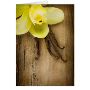 Vaniljpoder och blomma över träbakgrund hälsningskort