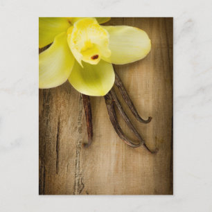 Vaniljpoder och blomma över träbakgrund vykort
