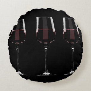 Vin-glas med rött vin på svart rund kudde