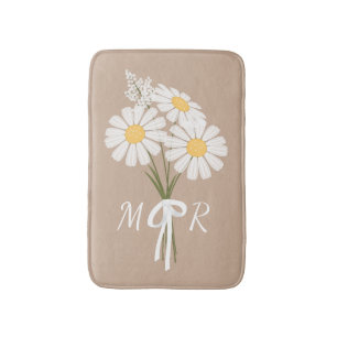 Vit bukett med tusenskönor och monogram på beige badrumsmatta