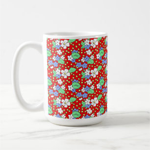 Vita och blå blommor på röd kaffekopp