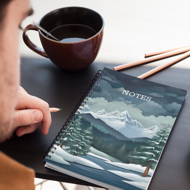 Winter Forest Scene Anteckningsbok (A snowy forest mountain scene notebook on a desk with pencils and coffee.)